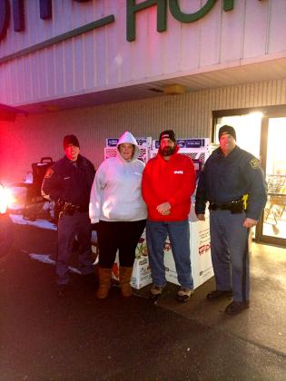 Anthony Dzanbozoff and his daughter Kennedy collect toys for Toys for Tots with the help of troopers from the Michigan State Police