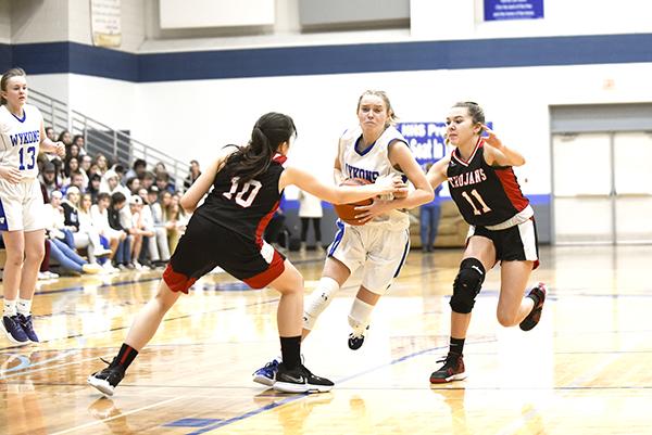 Wykons sophomore Danica Shamion drives into the lane as Lady Trojans senior Rayven Jacobson (#10) and sophomore Charlie Larson (#11) try to stop her.  Sophomore Haiden Gill (#13) waits on the outside for a possible kick-out. (Photo/Kevin Zini)