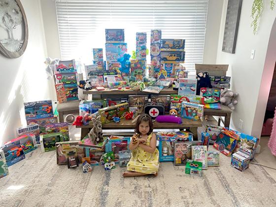 Preslie sits in front of a pile of toys to be donated to the Children's Hospital of Wisconsin.