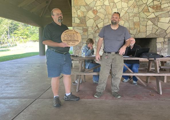 Courthouse custodian Robby Olson presents Mark Stauber, chair of the Iron County Board of Commissioners, with a hand-carved wooden plaque in honor of Pentoga Park’s 100th anniversary.  