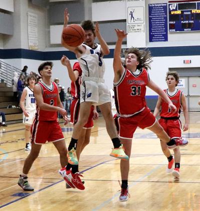 Brayden Marcell makes a big jump for a shot while defenders guard the hoop. 